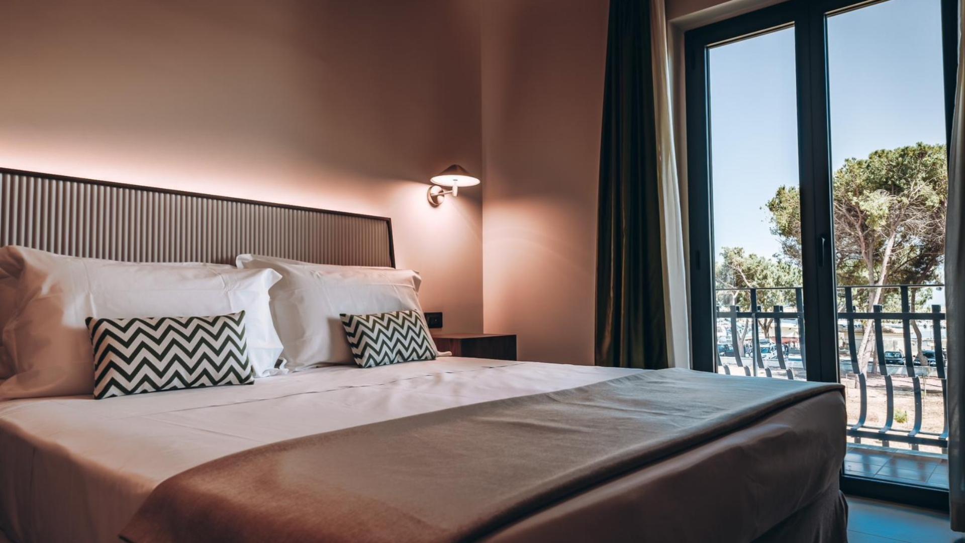 Camera da letto elegante con letto matrimoniale e vista su alberi dalla finestra.