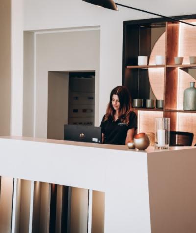 Reception moderna con arredamento elegante e una donna al computer.