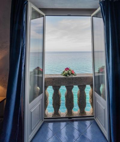 Vista mare da una finestra aperta con fiori sul balcone.
