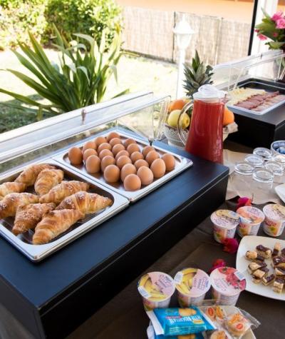 Buffet colazione con croissant, uova, frutta, yogurt e affettati all'aperto.