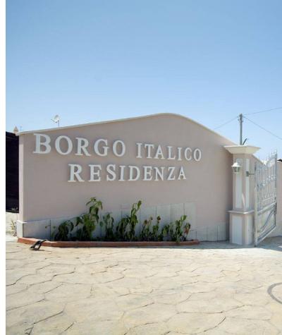 Ingresso della Residenza Borgo Italico con cancello e piante decorative.