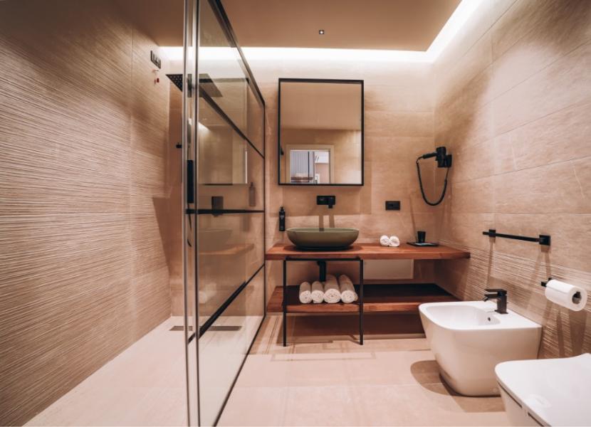 Bagno moderno con doccia, lavabo, bidet e illuminazione soffusa.