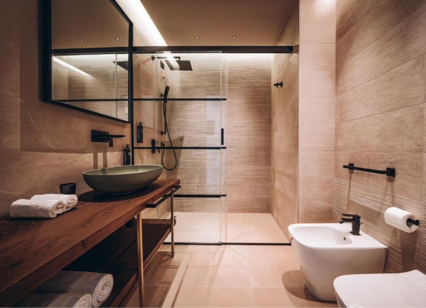 Bagno moderno con doccia in vetro, lavabo elegante e piastrelle beige.