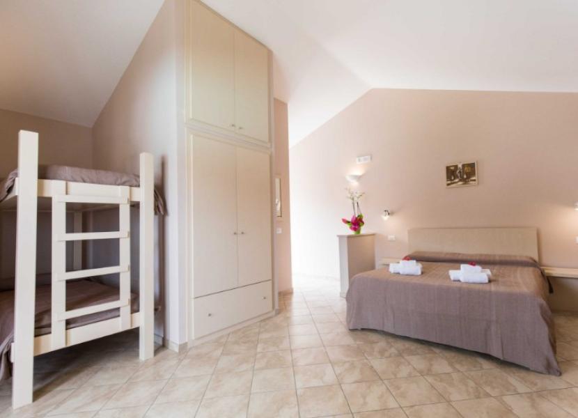 Camera minimalista con letto matrimoniale e letto a castello, armadio e decorazioni semplici.
