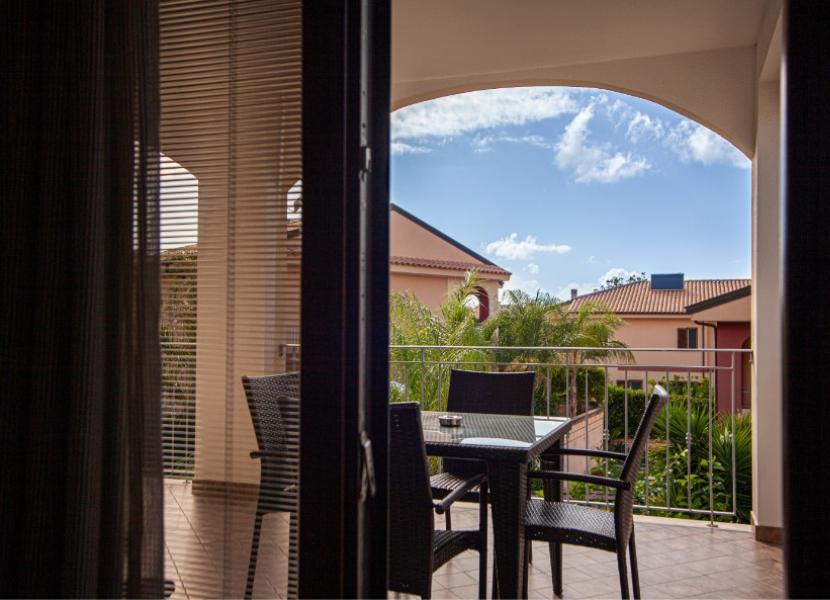 Vista su terrazza con mobili da esterno e villette sullo sfondo.