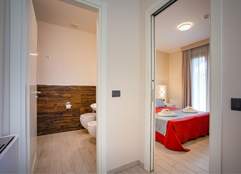 Camera moderna con bagno, arredamento minimalista e biancheria colorata.