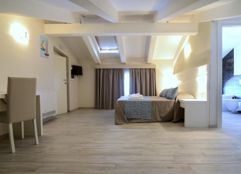 Camera moderna con letto matrimoniale, bagno privato e arredi chiari.
