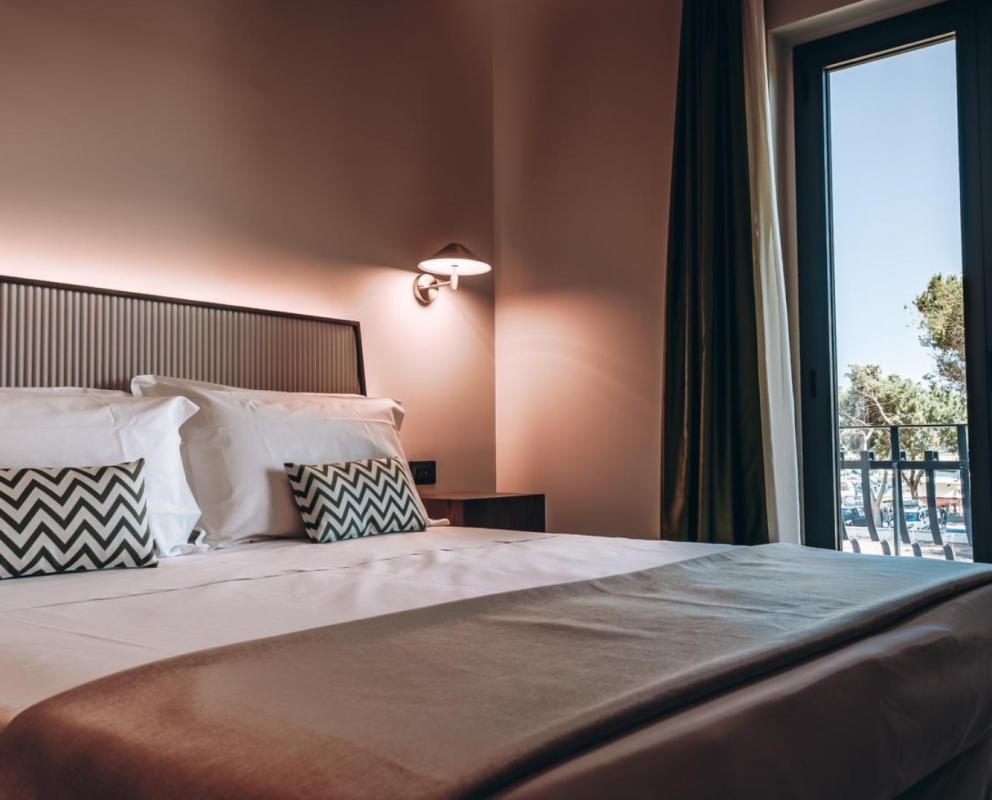 Camera da letto elegante con letto matrimoniale e vista su alberi dalla finestra.